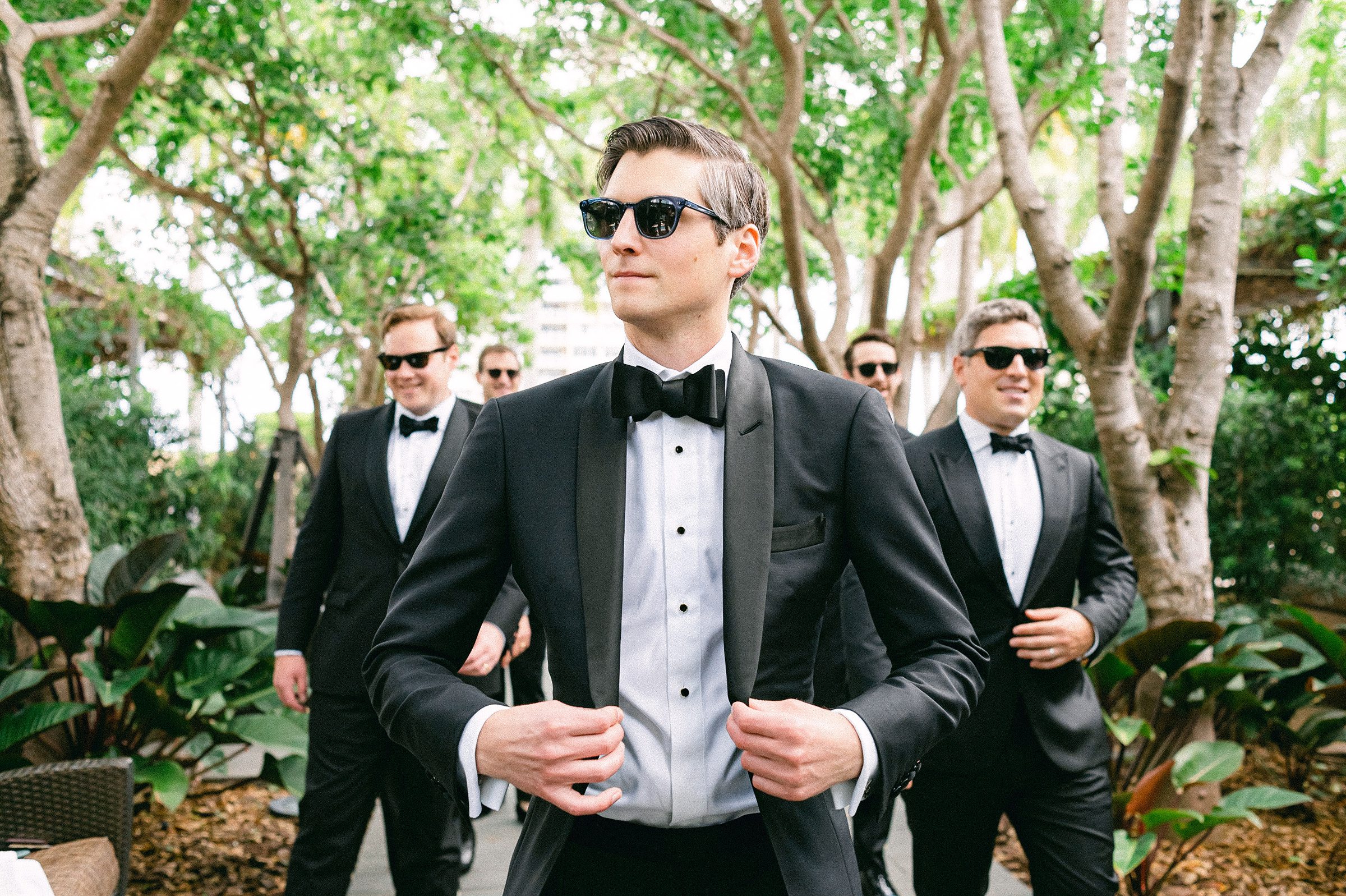 candid photo of the groom and groomsmen walking with Ray Ban sunglasses at the Four Seasons Brickell Miami