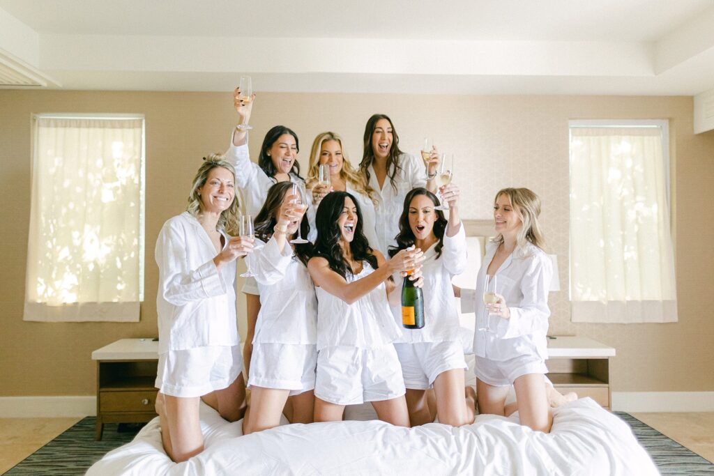 Bridesmaids popping champaign on the bed