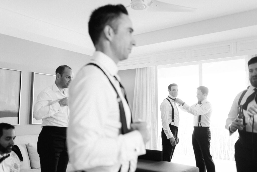 black and white candid 
photo of groomsmen getting ready in a layered composition