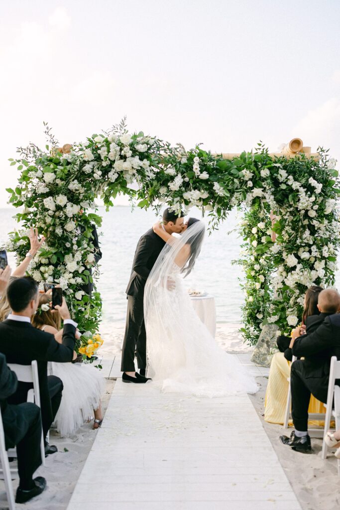 first kiss of the bride and groom under the white rose chuppah by Julia Rhode