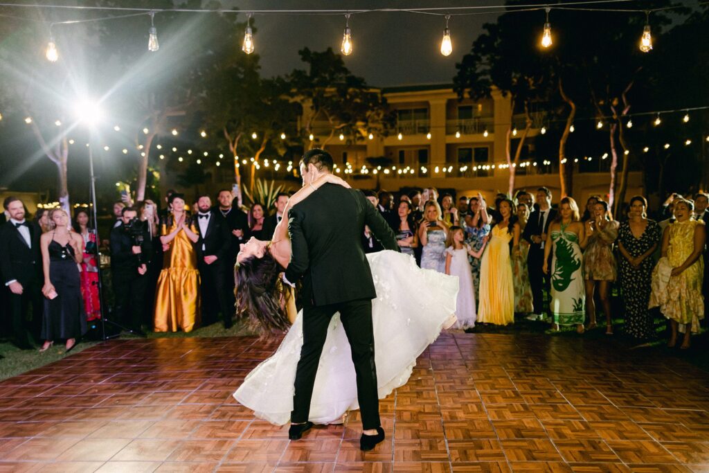 Groom dips bride during their first dance under the bistro lights on the Event Lawn of Playa Largo Resort