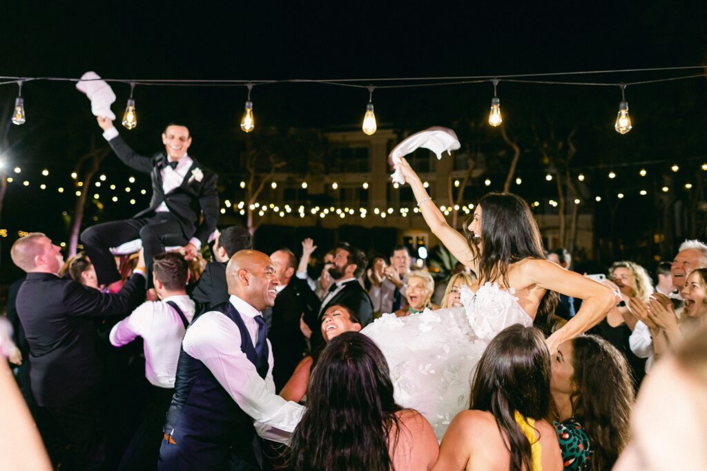 Bride and groom hoisted on chairs throwing white table napkins in the air