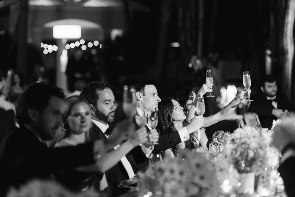 black and white image of the bride and groom raising a toast to the speaker