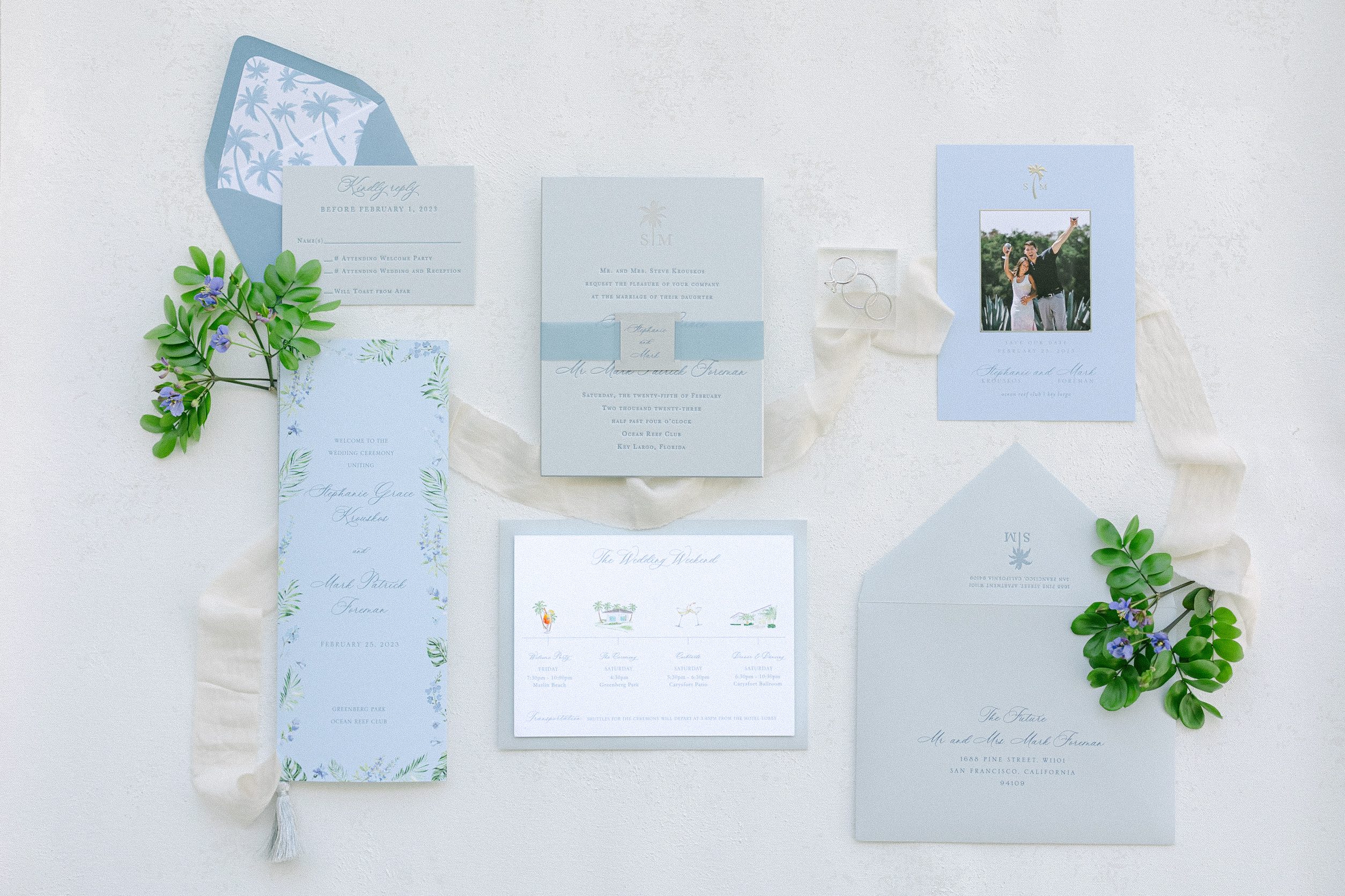 lay flat image of the wedding stationary and some greenery