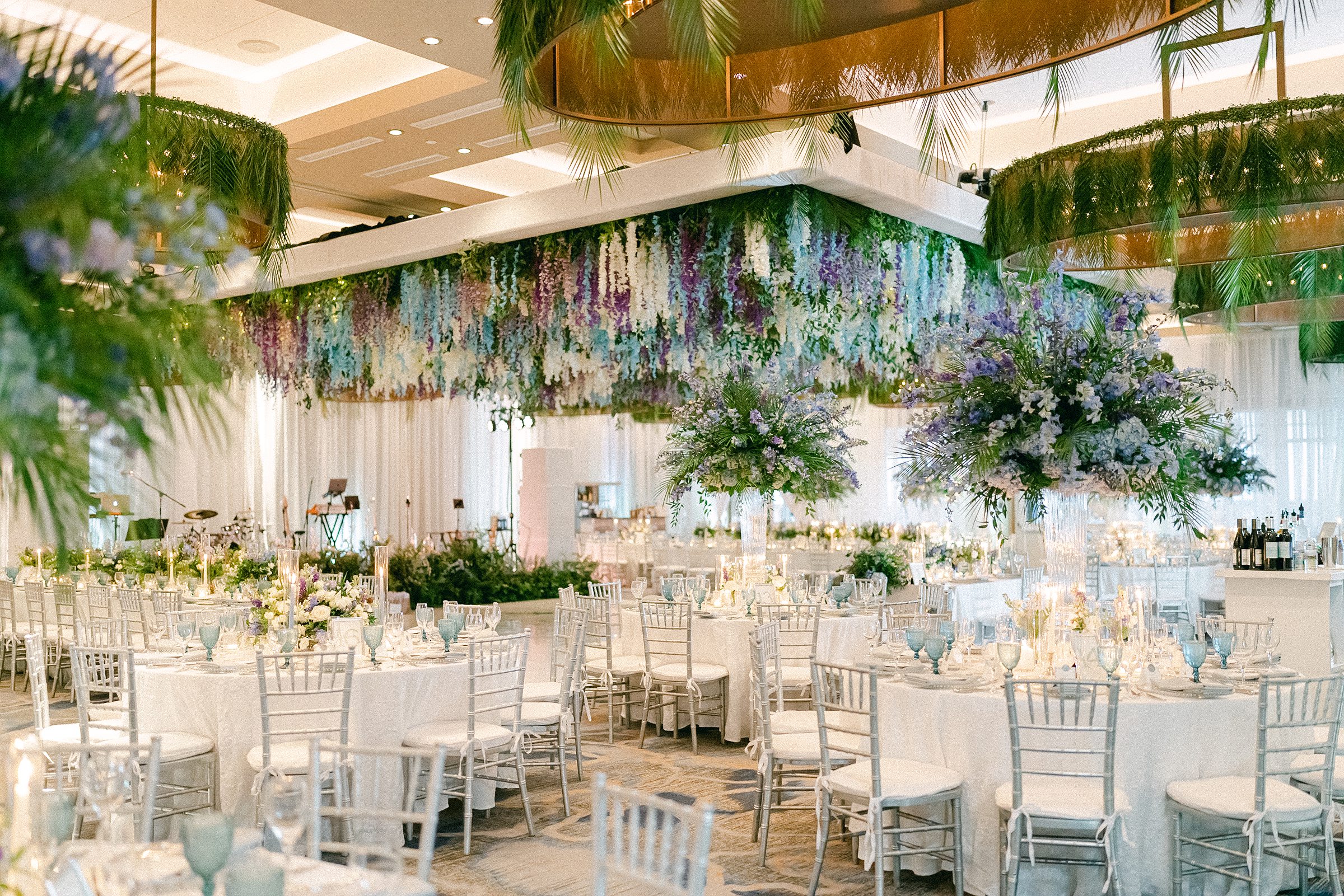 wide perspective image of the ocean reef club reception ballroom with white, soft blue, lilac Wisteria and greenery.