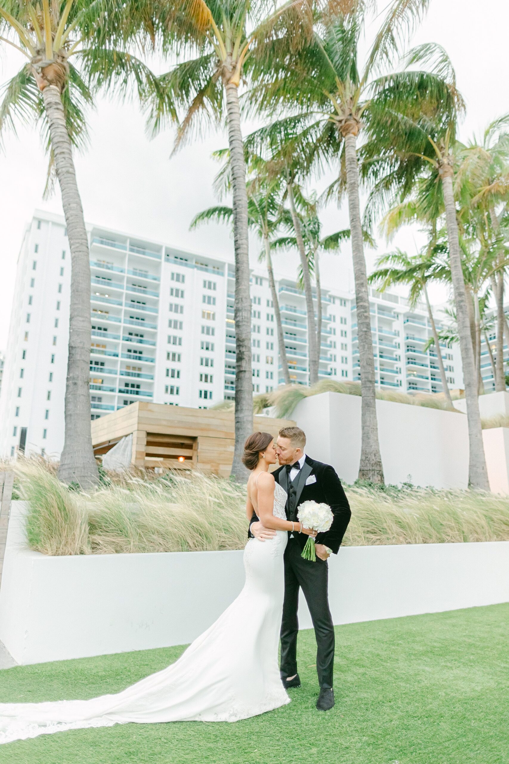 Portrait of newlyweds almost kissing on the green lawn with a background of palm trees at the 1Hotel South Beach