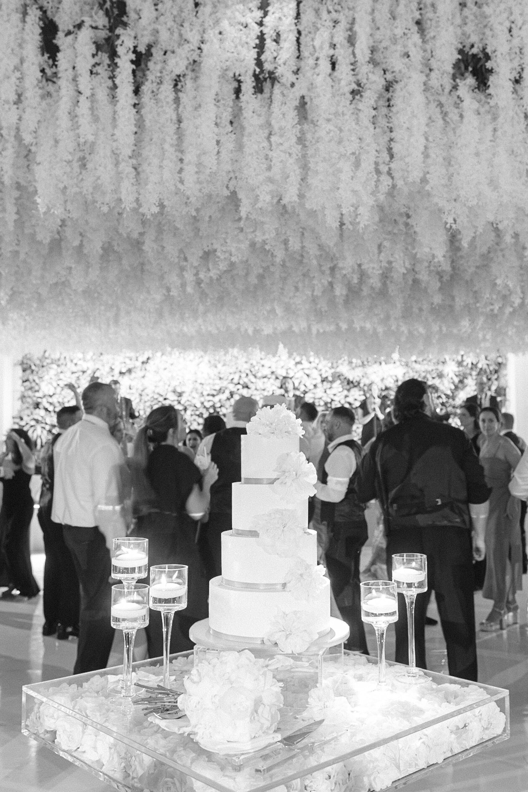 black and white image of the four tiered white cake in front of the dance floor