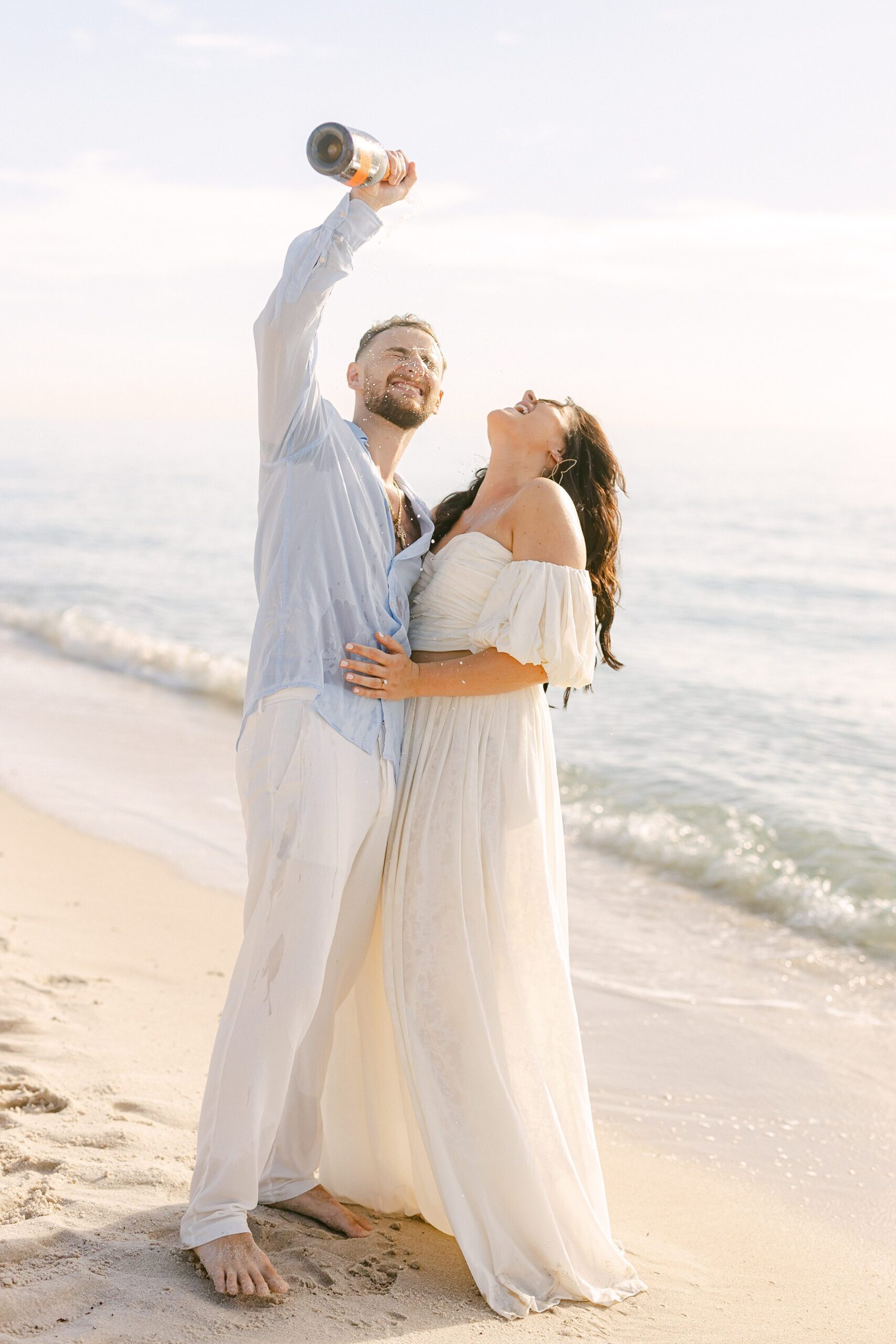 Engaged couple pouring champaign on each other at their sunrise portrait session in Miami Beach