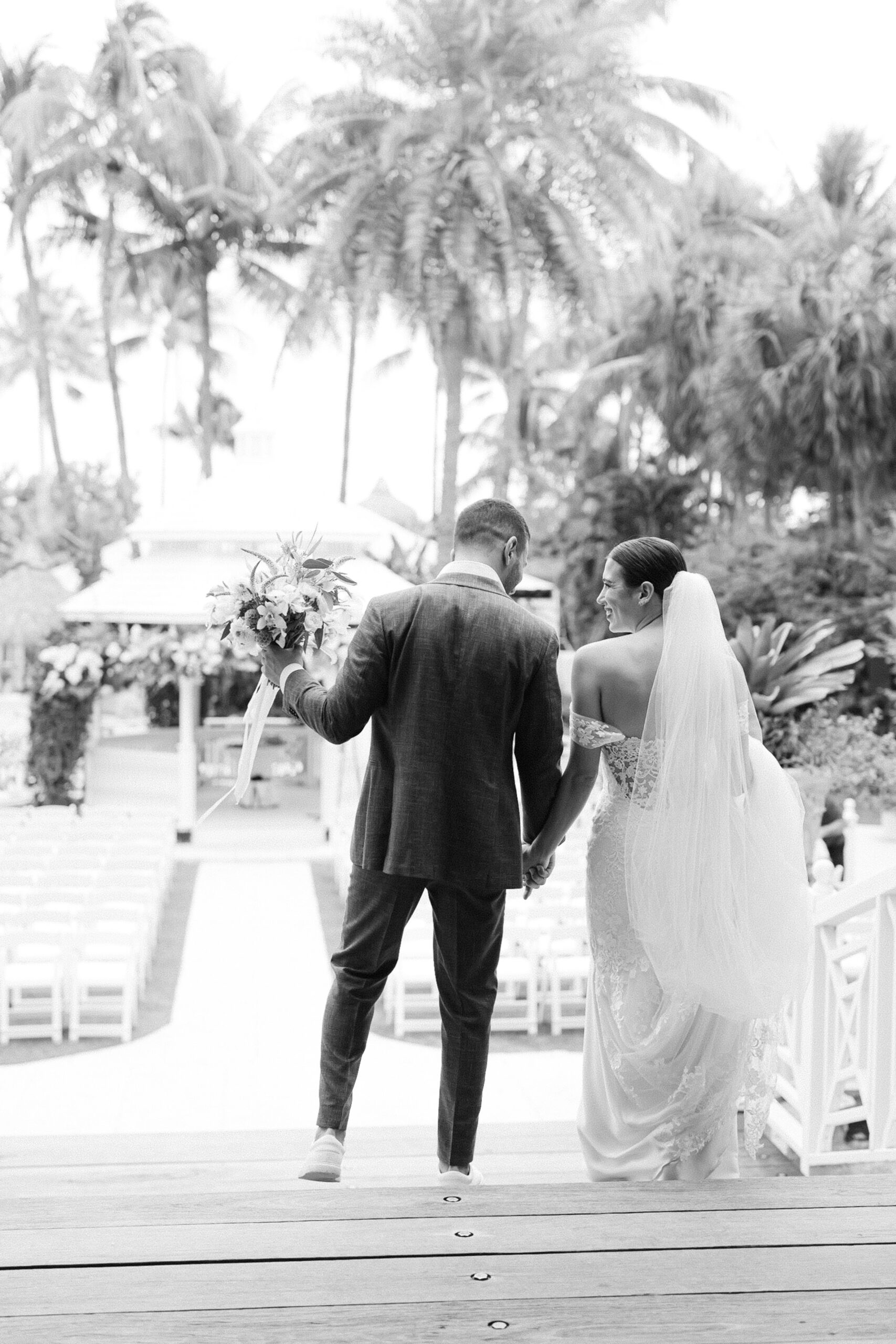 black and white image of the couple holding hands as they walk down the stairs