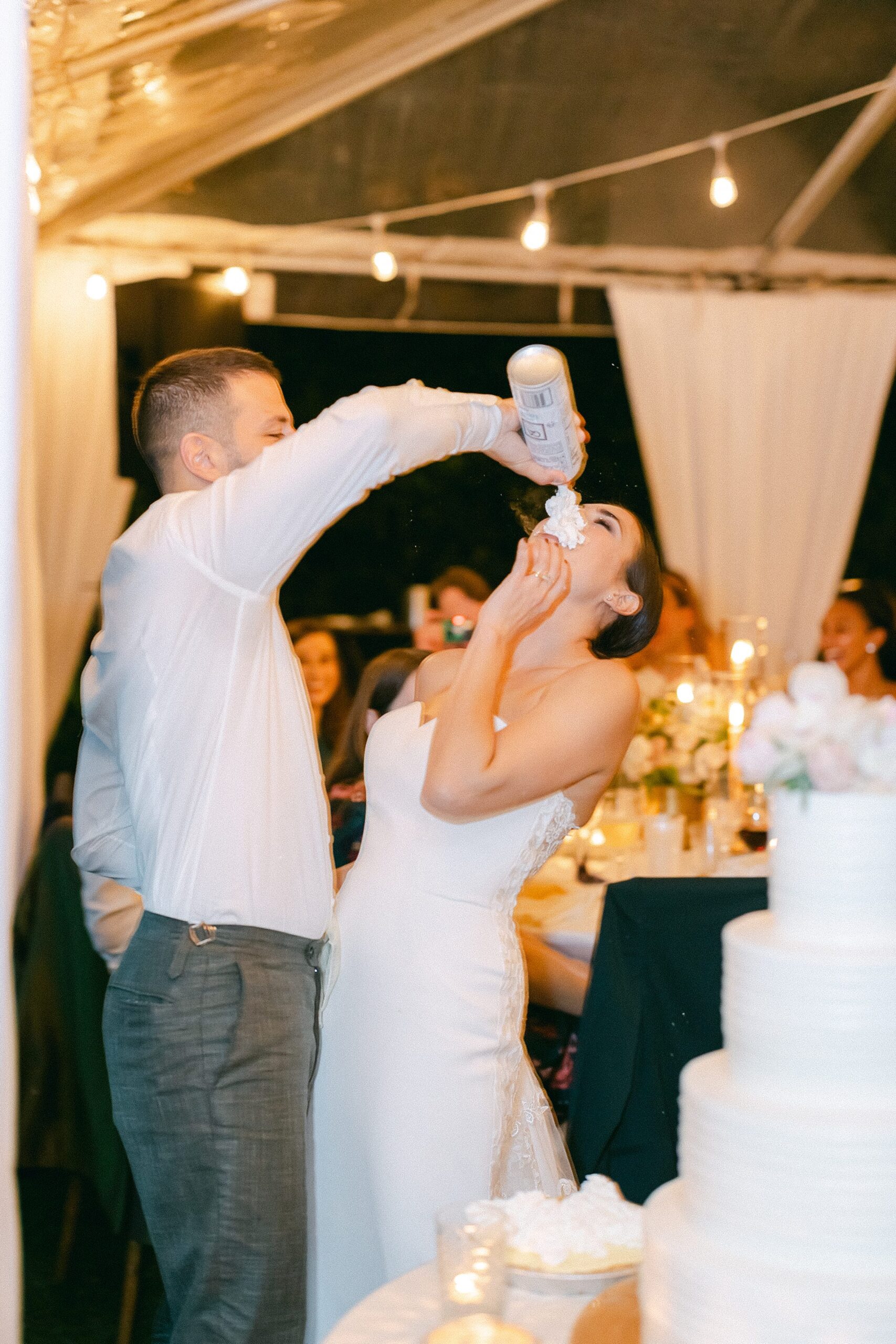 groom putting whip cream in the brides mouth at their cake cutting