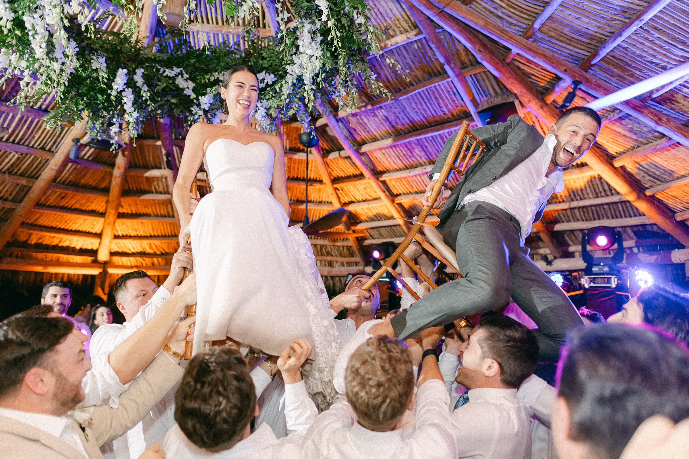 bride and groom being lifted onto chairs during the jewish hora 