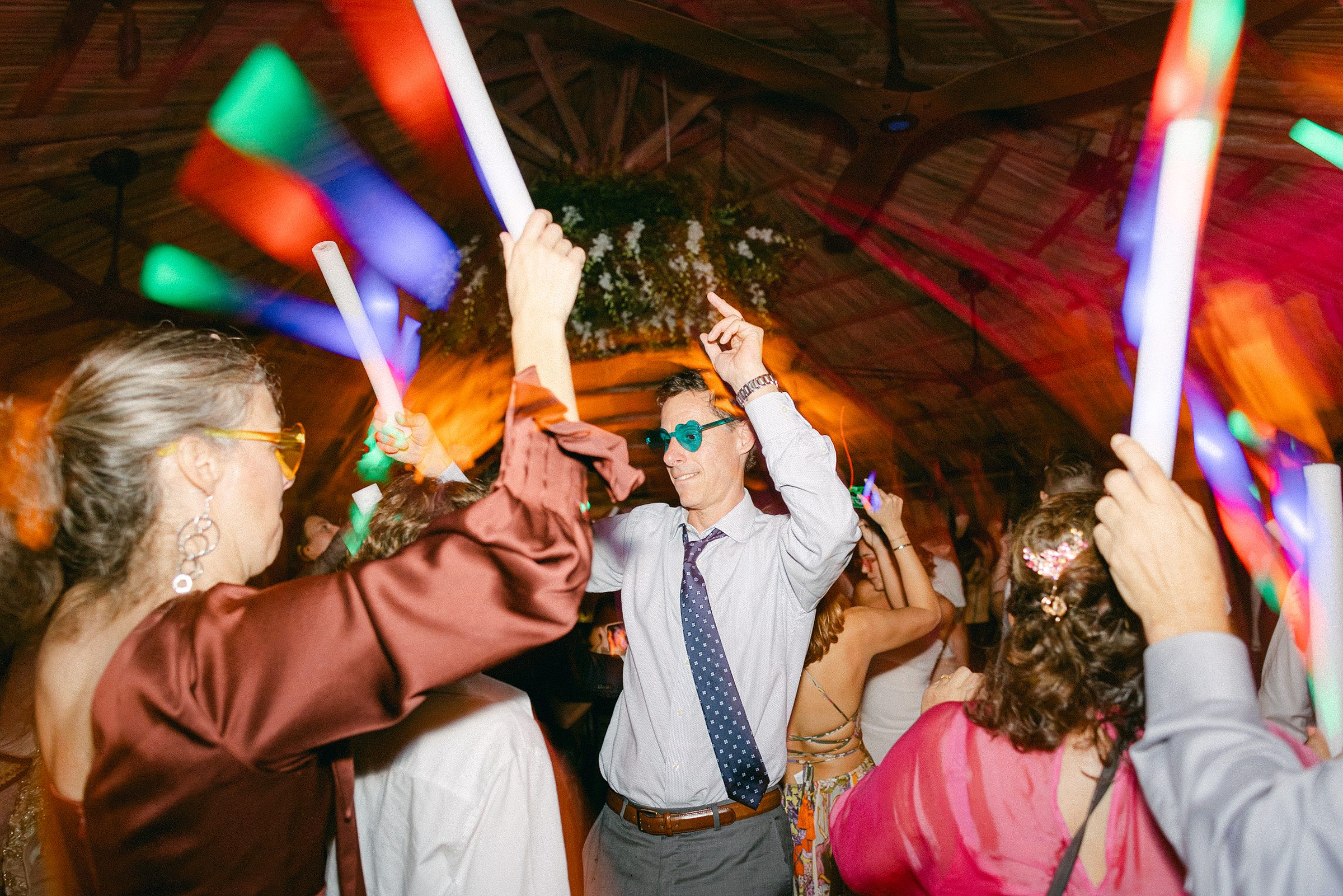 guests dancing with glow sticks and colored sunglasses