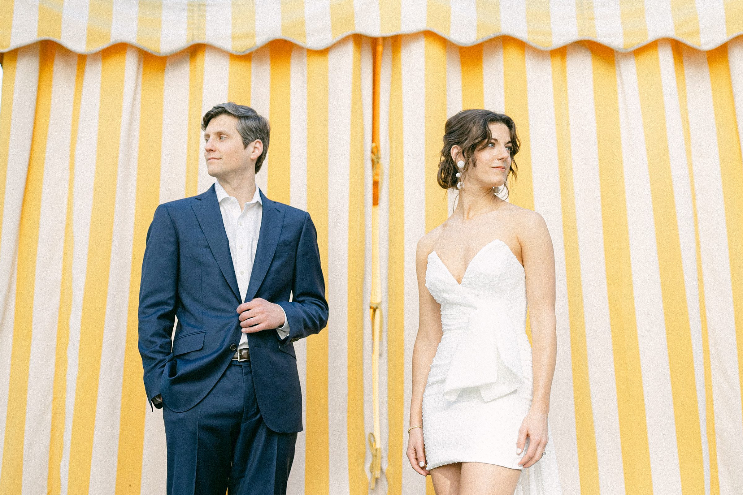 engaged couple posing in front of yellow and white stripped cabanas