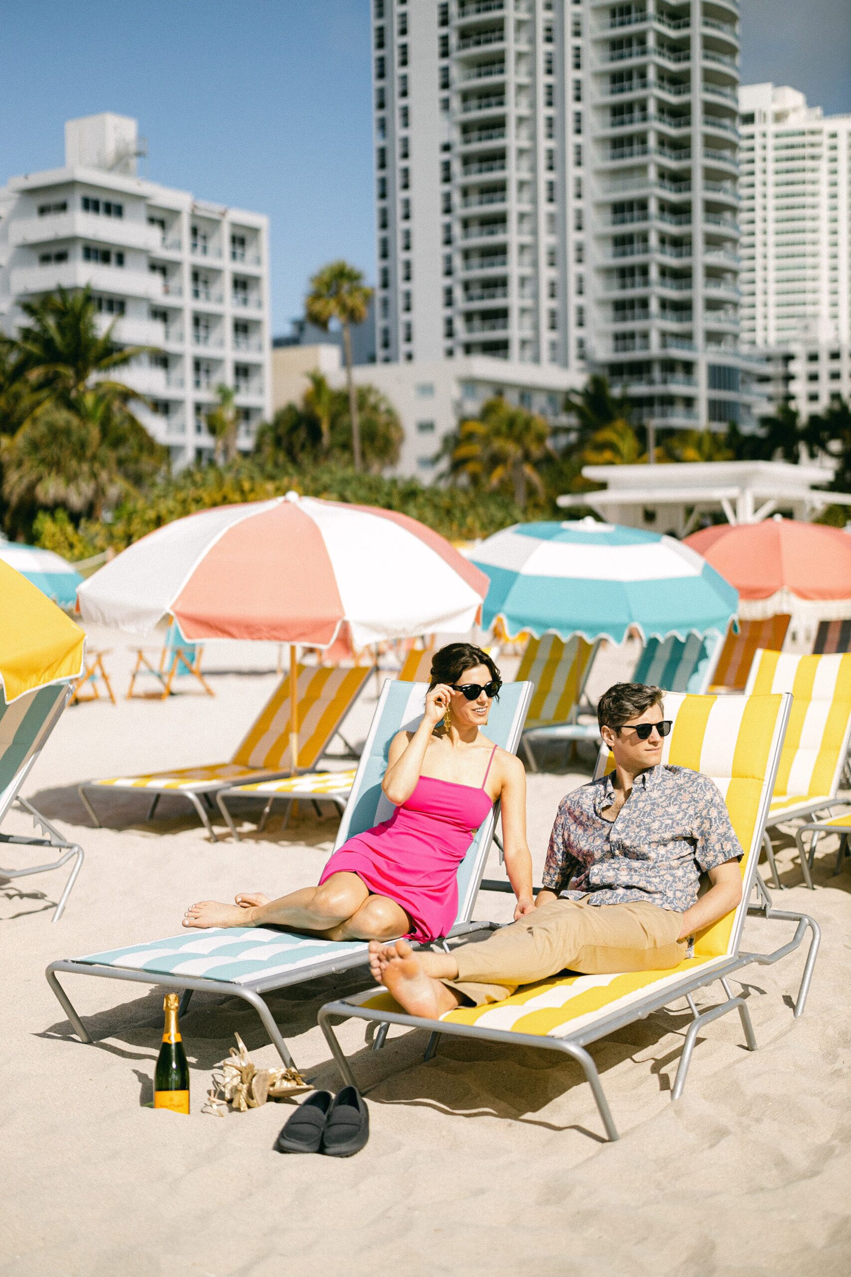 The engaged couple sitting at the iconic art deco lounge chairs at The Confidante Hotel in MIami Beach.