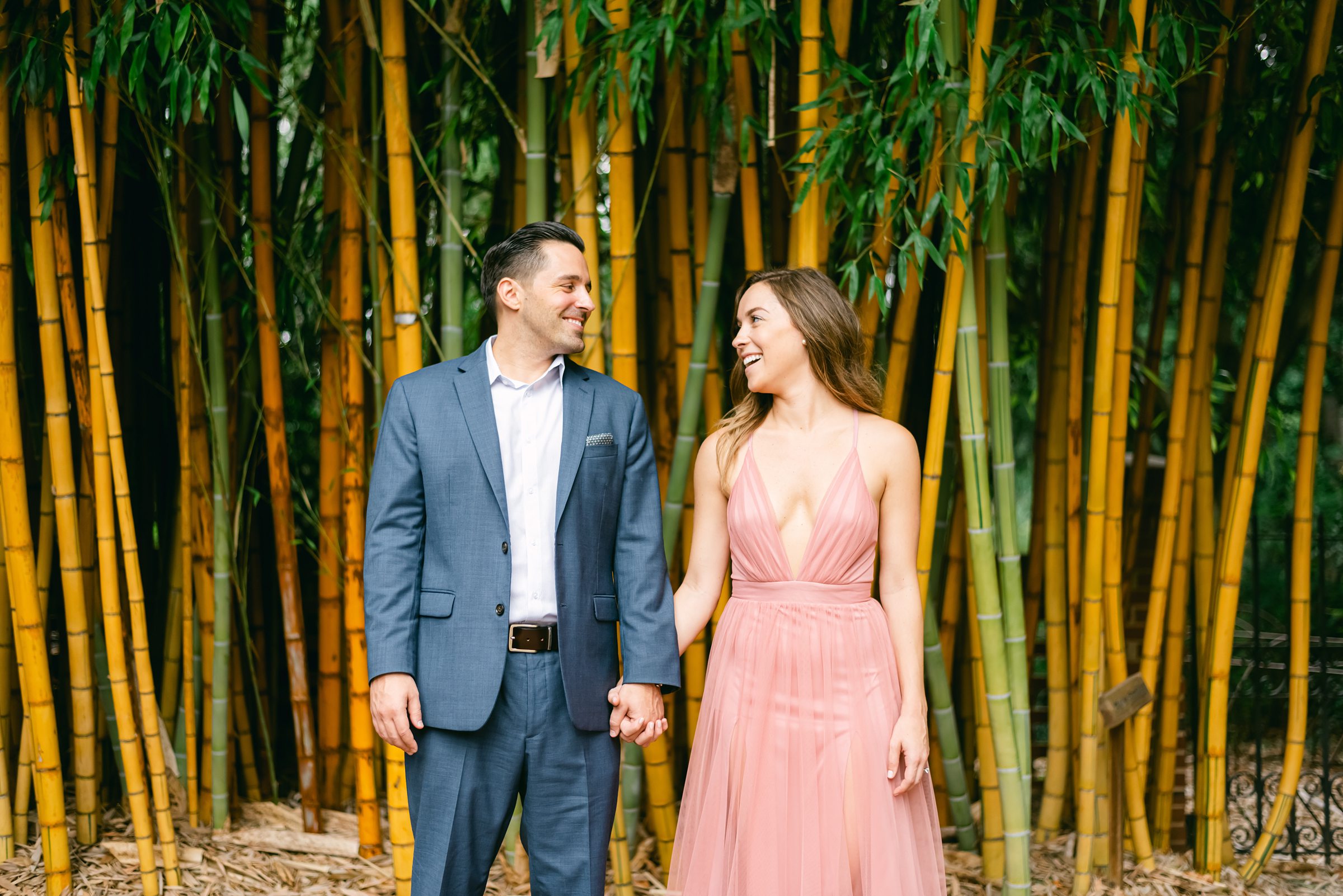 the couple looking at each other lovingly in front of orange bamboo trees.